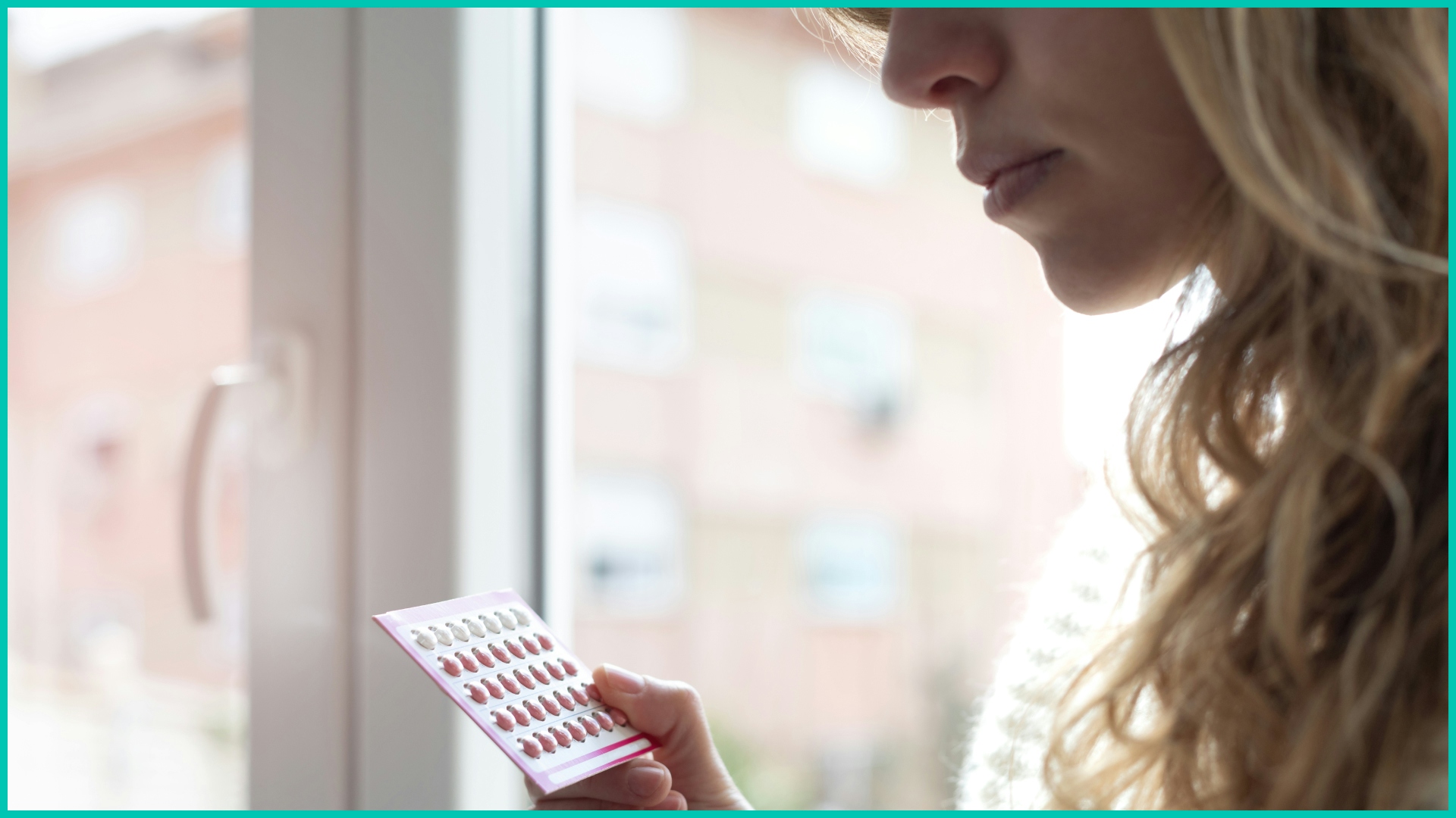 Blonde woman looking at a pack of birth control pills