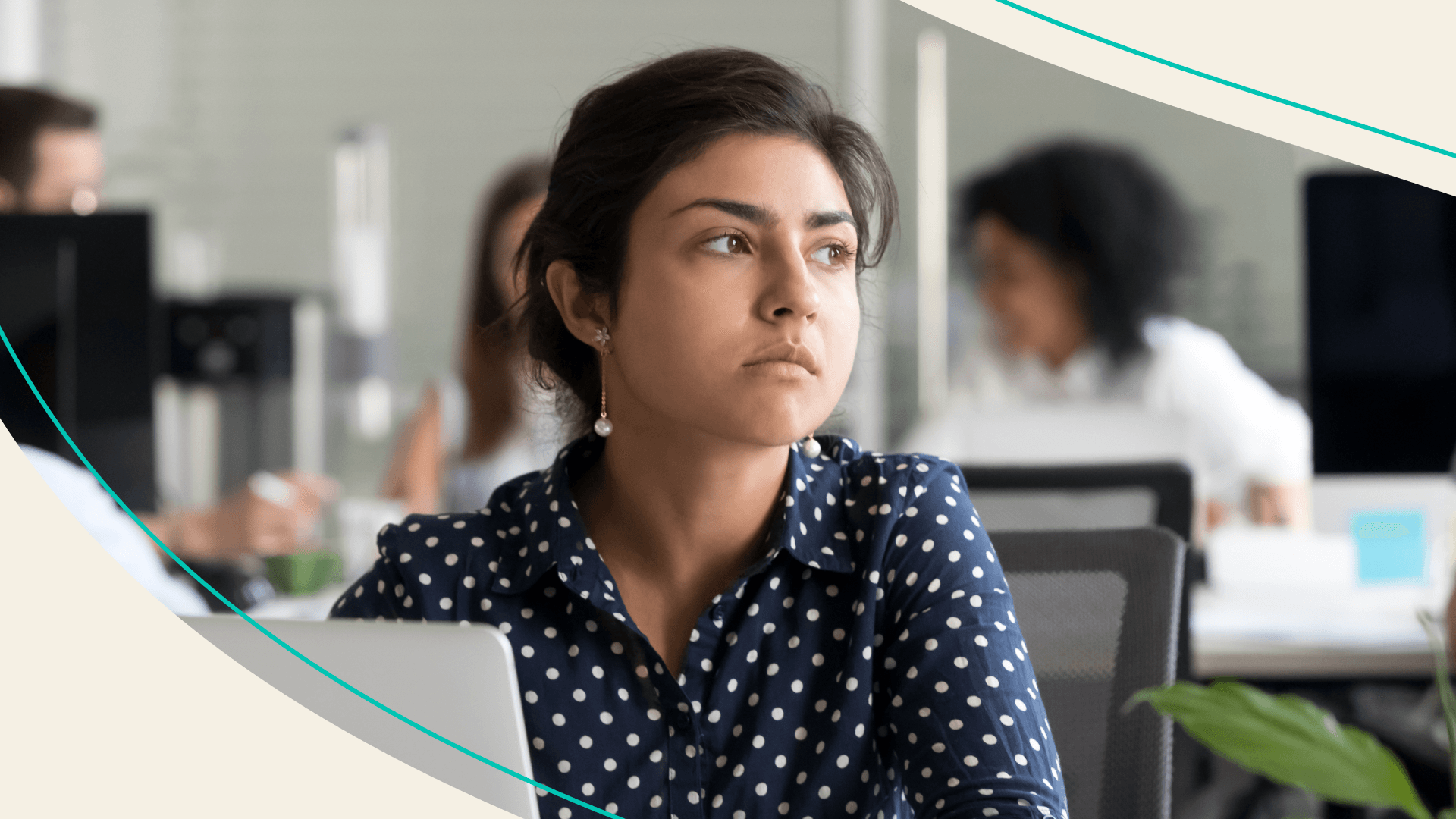 A woman at her desk at work staring off absent-mindedly