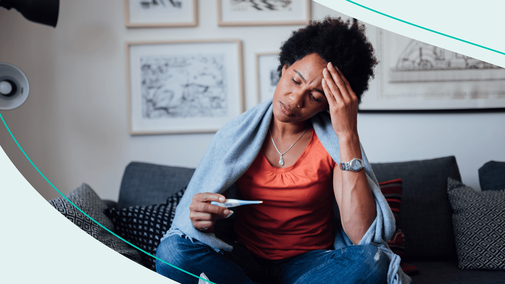 A woman sitting on a couch with a blanket over her shoulders, reading a thermometer